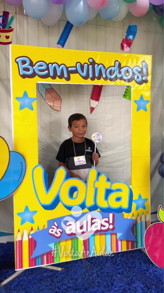 Criança a posar numa moldura amarela de «Volta às aulas», com texto sobre o início do ano letivo de 2026 em Boca do Acre.